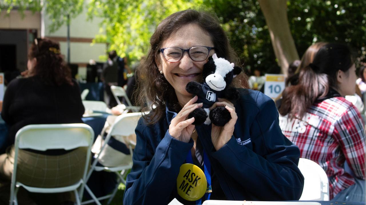 Advisor smiling with a stuffed animal cow