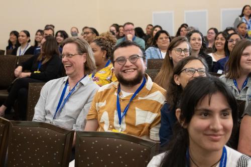 Conferencegoers in their seats smiling.