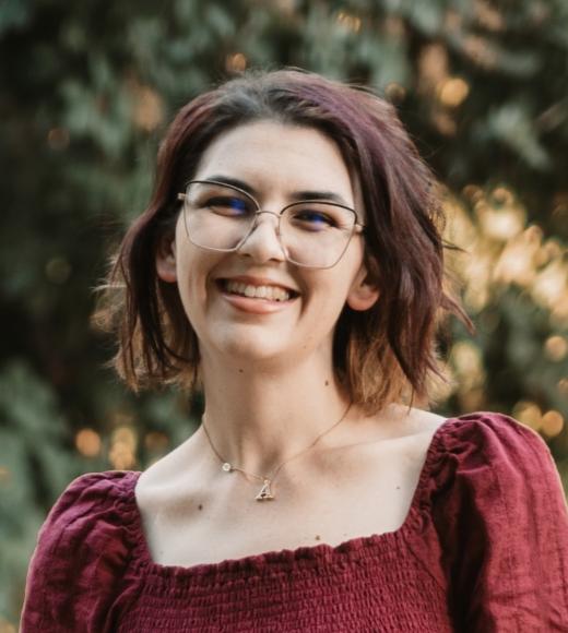 Ashley Pelham smiling in foreground, nature in background.