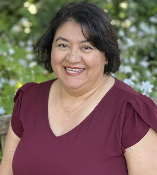 Maria Saldana smiling in foreground, nature in background.