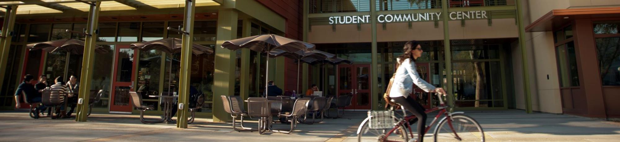 Cyclist passes Student Community Center.