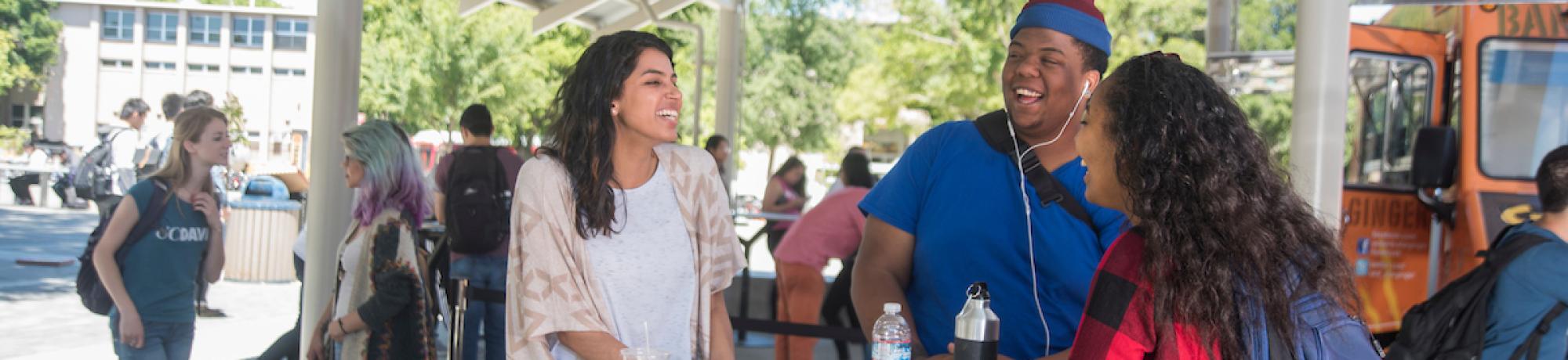 Students gathered around table near food trucks.
